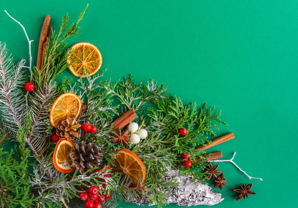 Noel, yeni yıl kartı - köknar, koni, kar, tarçın, yeşil arka planda böğürtlen. Düz konum, boşluk kopyala, üst görünüm