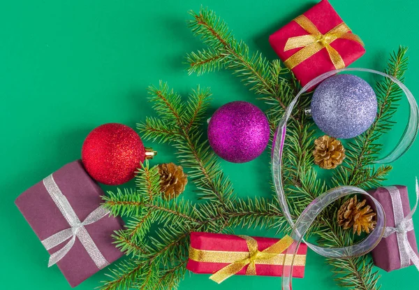 La Navidad, la tarjeta de Año Nuevo - los regalos, las bolitas, el abeto, los conos sobre el fondo verde. Colocación plana, espacio para copiar, vista superior —  Fotos de Stock