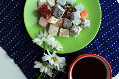 Türk lokumu ve yeşil zemin üzerine taze papatya tatlılar