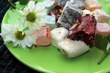 Türk lokumu ve yeşil zemin üzerine taze papatya tatlılar