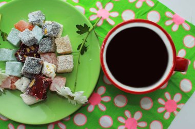 Kahvaltı kavramı kırmızı bir fincan, Türk lokumu ve yeşil zemin üzerine taze papatya sıcak çay ile