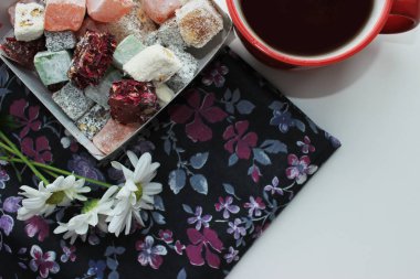 Kahvaltı kavramı kırmızı bir fincan, Türk lokumu ve koyu arka plan üzerinde taze papatya sıcak çay ile