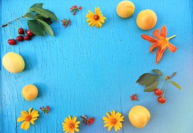 Olgun taze kayısı ve kiraz ahşap masa turkuaz yakın çekim parlak yaz çiçek ile. Üstten yatay görünüm. Kopya alanı