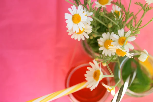 Summer break with bright cocktails and wildflowers on pink bright background. Copy space