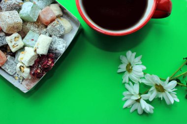 Tatlılar, Türk Lokumu, sıcak kahve ve taze papatya parlak yeşil zemin üzerine. Kahvaltı konsepti