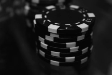 Poker oyunu. Siyah ve beyaz poker fişleri tek renkli etkisi ile. Yakın çekim