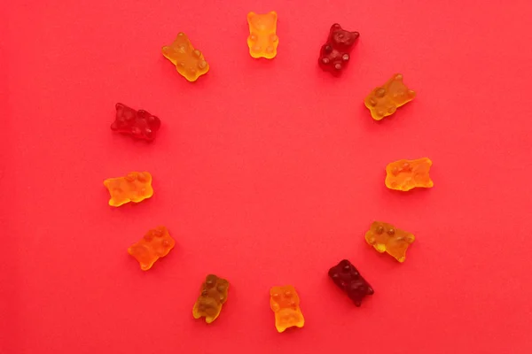Gummy bears in different colors. Concept babies. Rainbow circle of colored sweet gummy bears on pink background, copy space.