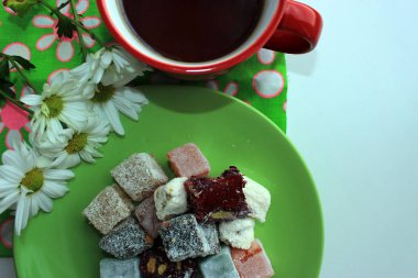 Sabah kırmızı bir fincan, Türk lokumu ve yeşil zemin üzerine taze papatya sıcak çay ile. Üstten görünüm