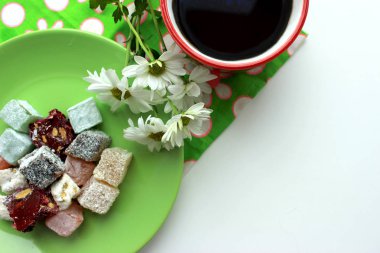 Kırmızı bir fincan, Türk lokumu ve yeşil zemin üzerine taze papatya sıcak çay ile Servis Kahvaltı. Üstten görünüm, kopya alanı