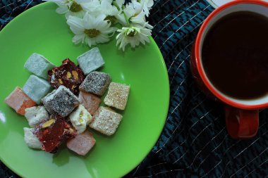 Kırmızı bir fincan, Türk lokumu ve yeşil zemin üzerine taze papatya sıcak çay ile Servis Kahvaltı. Üstten görünüm