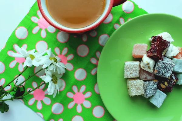 Sonbahar coziness. Kırmızı bir fincan, Türk lokumu ve yeşil zemin üzerine taze papatya sıcak çay ile Servis Kahvaltı. Üstten görünüm