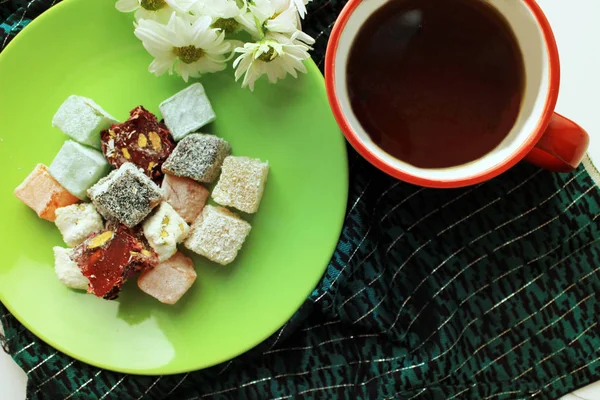 Kırmızı bir fincan, Türk lokumu ve yeşil zemin üzerine taze papatya sıcak çay ile Servis Kahvaltı. Üstten görünüm