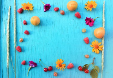 Besin zengin meyve. Olgun taze kayısı, Bektaşi üzümü ve ahududu ahşap masa turkuaz yakın çekim ve parlak çiçekler yaz. Üstten yatay görünüm. Metin için yer kopyalayın