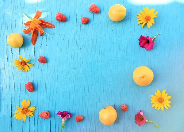 Besin zengin meyve. Olgun taze kayısı ve ahududu ahşap turkuaz yakın çekim ve yaz çiçek masa. Üstten yatay görünüm. Metin için yer kopyalayın
