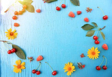 Çilek: kiraz, ahududu ahşap turkuaz tablo yakın-up sarı yaz çiçekleri ile. Üst görünüm. Boşluk Kopyala