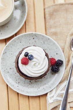 Fransız tatlısı- böğürtlenli kek ve bir fincan kapuçino. Terasta sıcak bir kahvaltı.