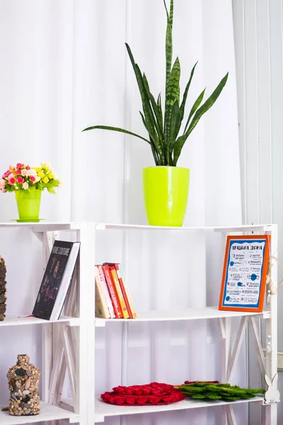 White bookshelf flowers magazines basket violets interior design room