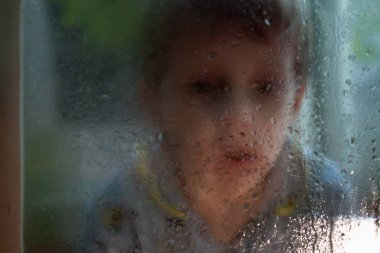 damla ile cam dan bir çocuğun üzücü portre. Çocuk cama dokunur.