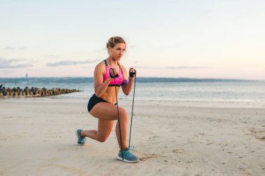 kulaklıklar içinde sporcumuz ile Sahil bandında germe ile egzersiz yaparak omuz çantası içinde smartphone 