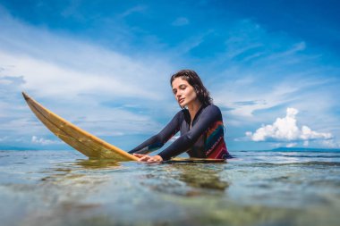 portrait of young sportswoman in wetsuit on surfing board in ocean at Nusa dua Beach, Bali, Indonesia clipart