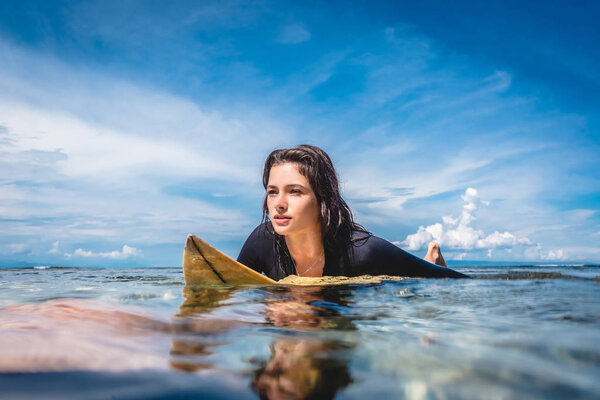 молодая спортсменка в гидрокостюме на доске для серфинга в океане на пляже Нуса Дуа, Бали, Индонезия

