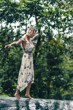içinde yeşil bitkiler ile yüzme havuzu yakındaki arka planda, ubud, bali, Endonezya yürüme çekici sarışın kadın