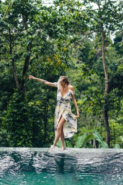 içinde yeşil bitkiler ile yüzme havuzu yakındaki arka planda, ubud, bali, Endonezya yürüme çekici sarışın kadın
