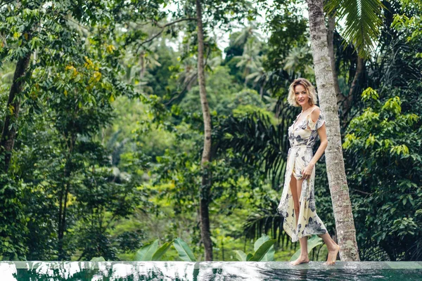 Atractiva Mujer Rubia Vestido Caminando Cerca Piscina Con Plantas Verdes — Foto de Stock