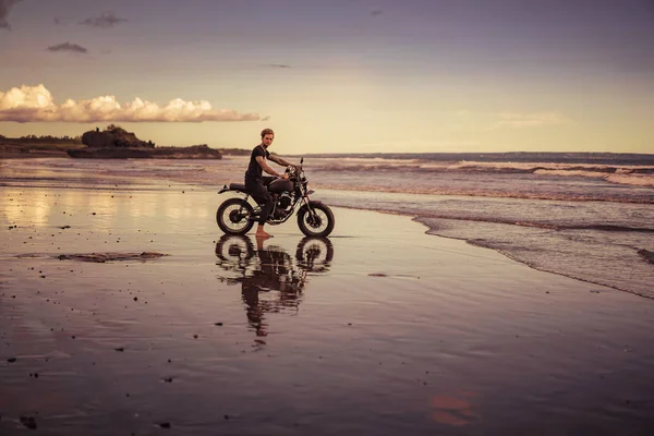 Guapo Ciclista Tatuado Sentado Moto Playa Del Océano Durante Amanecer — Foto de stock gratuita