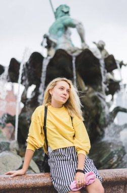 young woman looking away in front of Neptunbrunne in Berlin, Germany  clipart