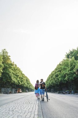 sırt çantaları ve Berlin, Almanya'da Street Yürüyüş Bisiklet turist çiftin arka görünüm 