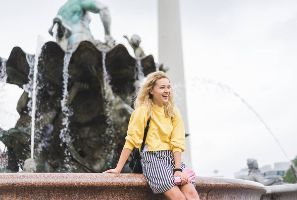 happy young woman in front of Neptunbrunne, Berlin, Germany 