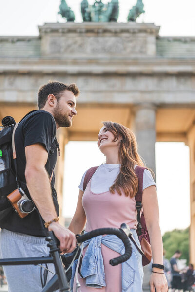 low angle view of travelers with backpacks and bicycle in front of Brandenburg Gate, Berlin, Germany 