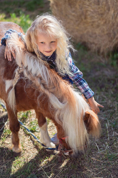 preteen child hugging cute pony at farm