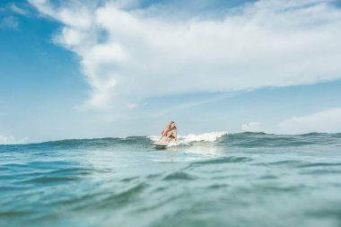 Nusa Dua Beach, Bali, Endonezya, okyanusta gemiye binme gömleksiz erkek sörfçü uzak görünümünü
