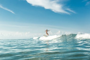 Erkek sörfçü Nusa Dua Beach, Bali, Endonezya, okyanusta dalgaları sürme uzak görünümünü