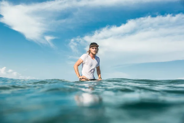 ヌサドゥア ビーチ インドネシアの海でサーフィン ボードの上に座って男性サーファー — ストック写真