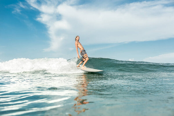 shirtless male surfer riding waves in ocean at Nusa Dua Beach, Bali, Indonesia