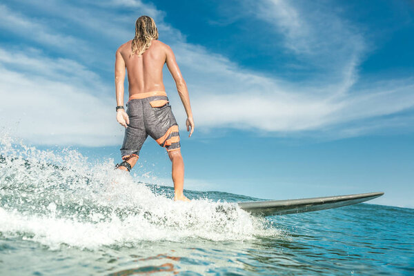 rear view of shirtless male surfer riding in ocean at Nusa Dua Beach, Bali, Indonesia