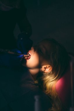 selective focus of dentist in latex gloves treating little kids teeth at dentist office clipart