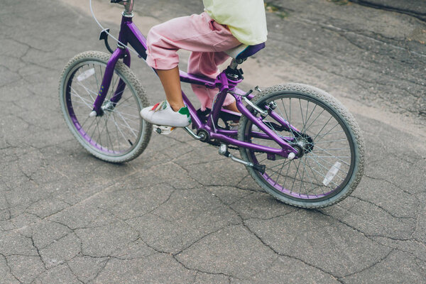 cropped shot of child riding bicycle on city street