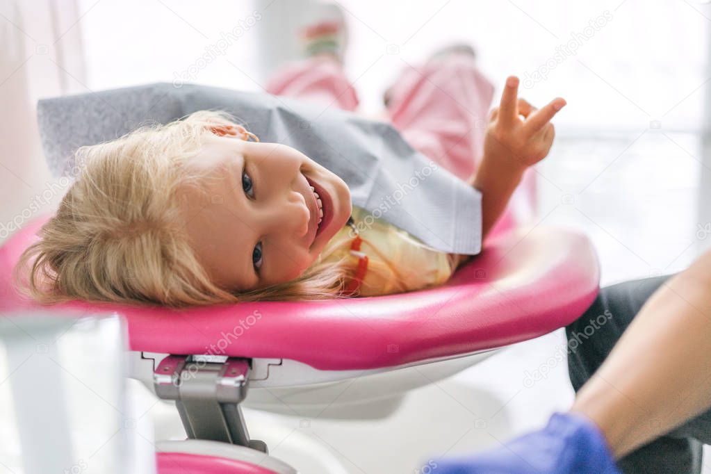 portrait of child showing peace sign at dentist office