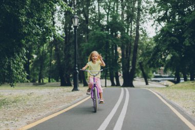 küçük çocuk barış işareti Bisiklet park de yol yaz gününde sürme sırasında gösterilen