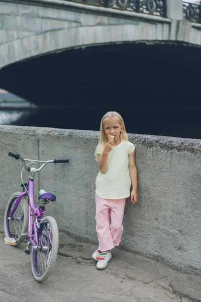 Niño Pequeño Comiendo Helado Mientras Está Pie Cerca Bicicleta Calle — Foto de stock gratis