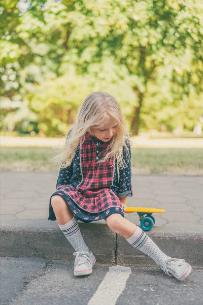 小さな子供が都市通りにあるスケート ボードの上に座って — ストック写真