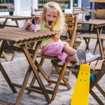 Selective focus of little child eating dessert at table near skateboard in cafe