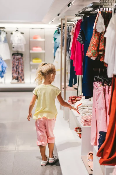 rear view of little child choosing clothes in shop