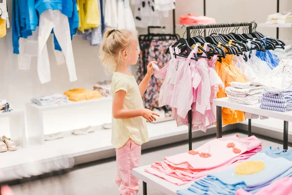 selective focus of adorable little child choosing clothes in shop