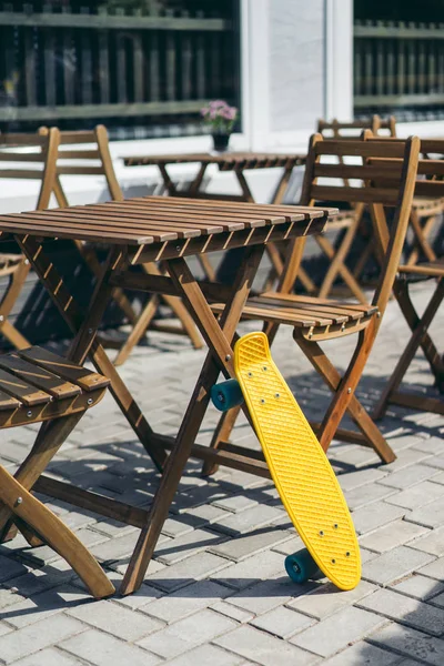 Selektiver Fokus Des Penny Boards Das Neben Tisch Und Stühlen — Stockfoto