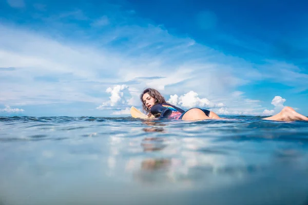 Vista lateral de la joven deportista en traje de neopreno en tabla de surf en el océano en Nusa dua Beach, Bali, Indonesia - foto de stock
